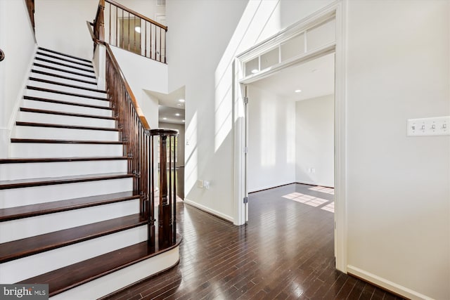 foyer featuring stairs, wood-type flooring, a towering ceiling, and baseboards