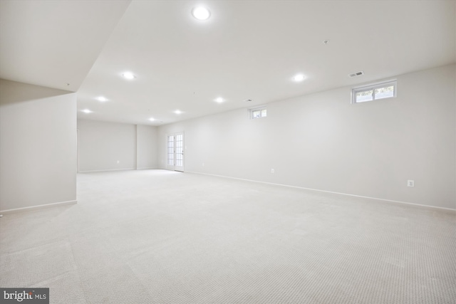 basement featuring light carpet, baseboards, visible vents, and recessed lighting