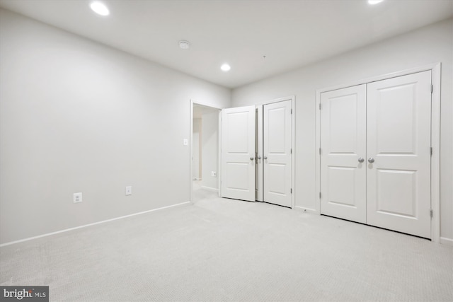 unfurnished bedroom with light carpet, baseboards, two closets, and recessed lighting