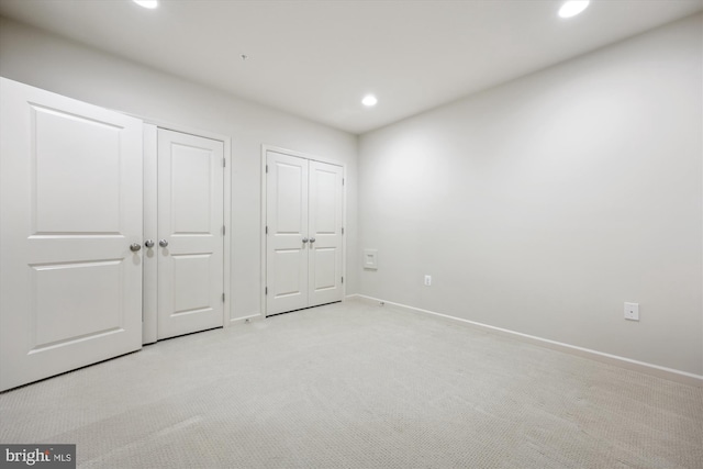 unfurnished bedroom with recessed lighting, baseboards, multiple closets, and light colored carpet