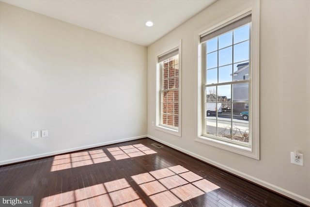 unfurnished room featuring hardwood / wood-style floors, visible vents, and baseboards