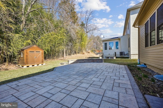 view of patio with an outbuilding, central air condition unit, and a shed