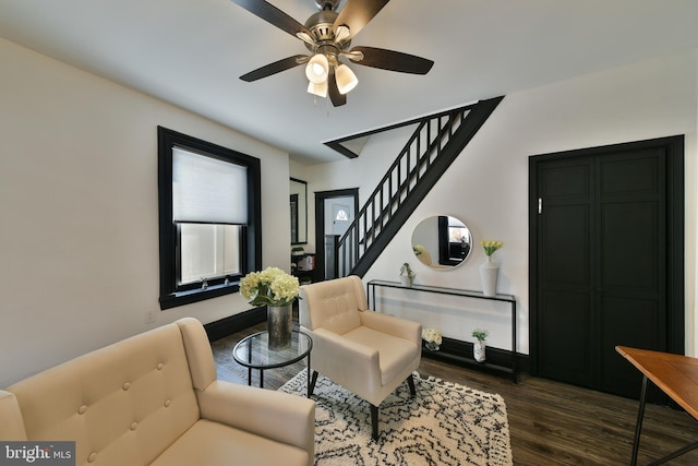 sitting room with ceiling fan, dark wood finished floors, and stairs