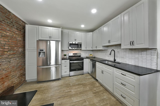 kitchen featuring appliances with stainless steel finishes, dark countertops, white cabinets, and a sink