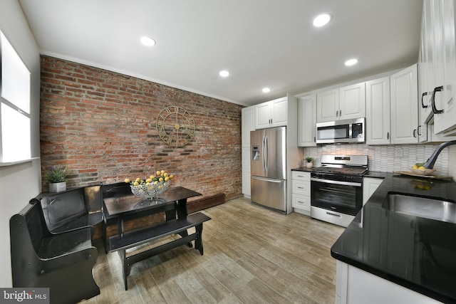 kitchen featuring stainless steel appliances, light wood-type flooring, dark countertops, and white cabinetry