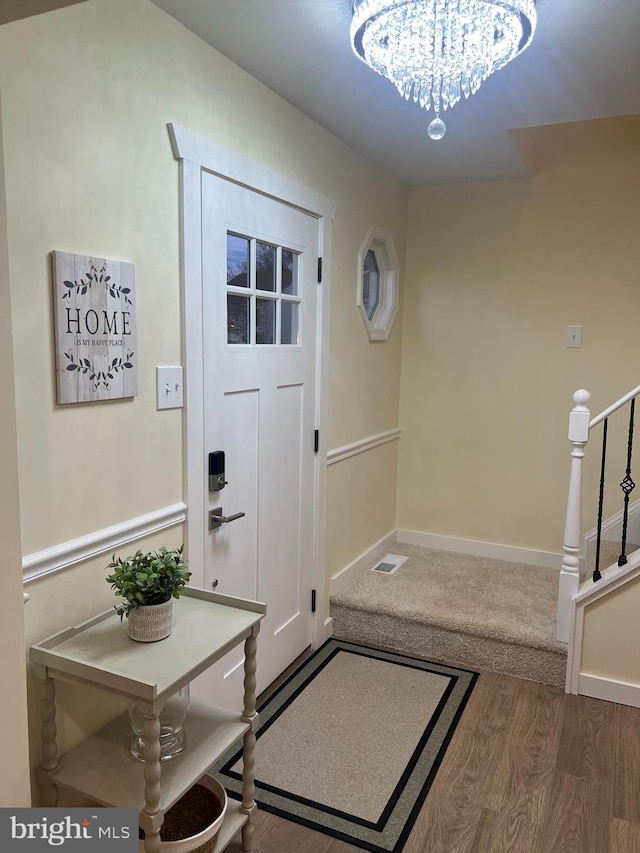 entryway featuring a notable chandelier, stairway, baseboards, and wood finished floors