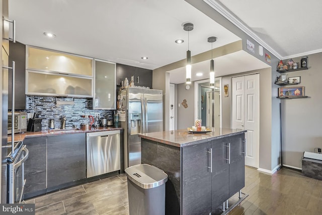 kitchen featuring stainless steel appliances, tasteful backsplash, hanging light fixtures, a sink, and modern cabinets