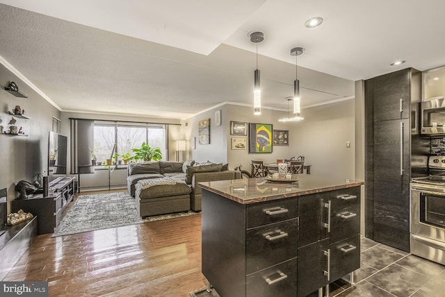 kitchen featuring a center island, crown molding, dark countertops, appliances with stainless steel finishes, and dark wood-type flooring