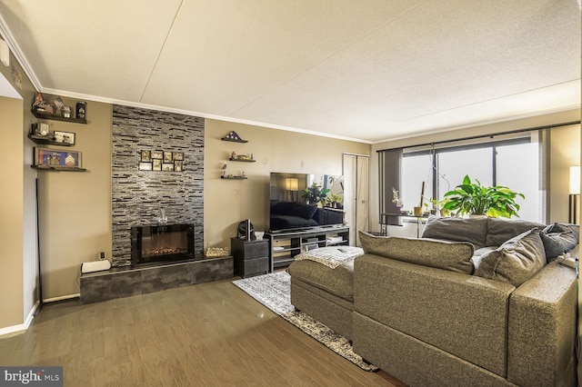 living area with a fireplace, crown molding, baseboards, and wood finished floors