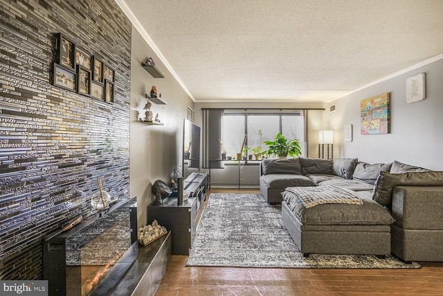 living room featuring a textured ceiling, an accent wall, wood finished floors, and crown molding