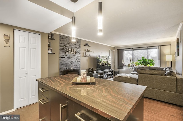 kitchen featuring dark countertops, light wood-style flooring, ornamental molding, open floor plan, and a kitchen island