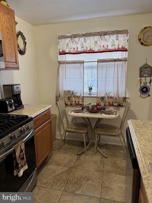 kitchen with baseboards, light countertops, brown cabinetry, and stainless steel appliances