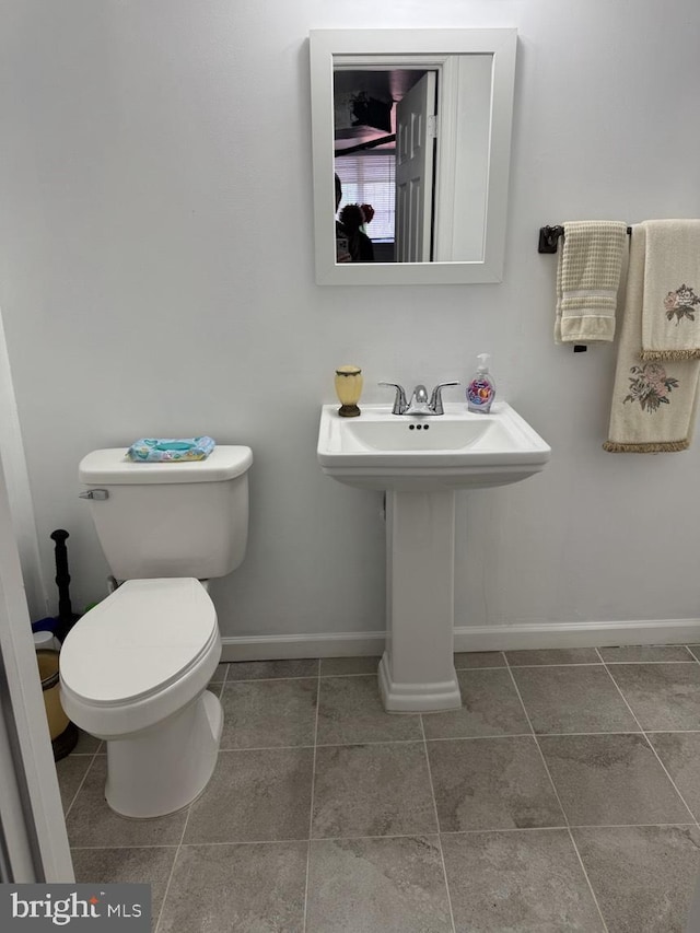 half bathroom with tile patterned flooring, toilet, and baseboards