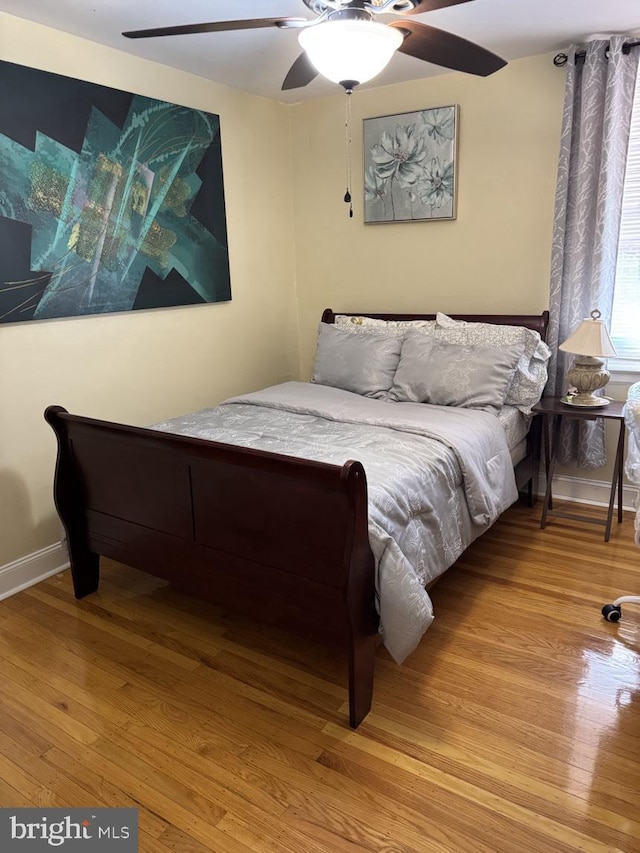 bedroom with ceiling fan, light wood-style flooring, and baseboards