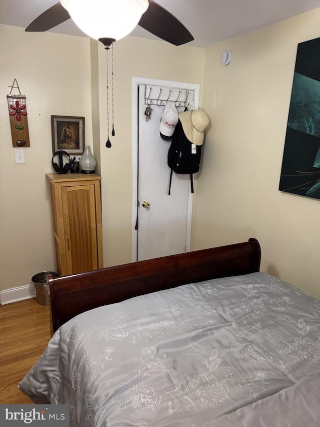 bedroom featuring wood finished floors, a ceiling fan, and baseboards