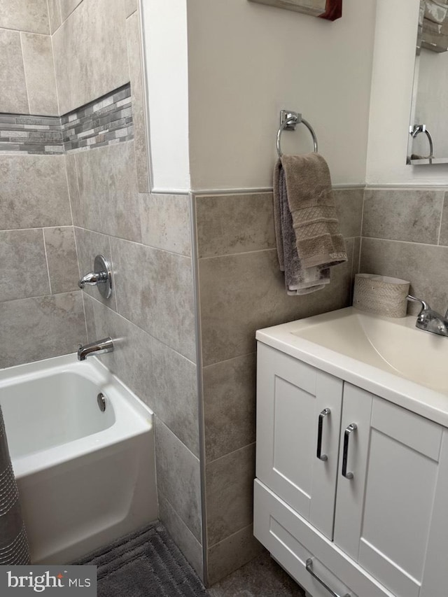 full bathroom with wainscoting, tub / shower combination, vanity, and tile walls