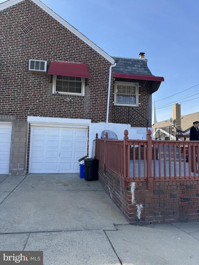 view of front of house with a high end roof, concrete driveway, brick siding, and an attached garage