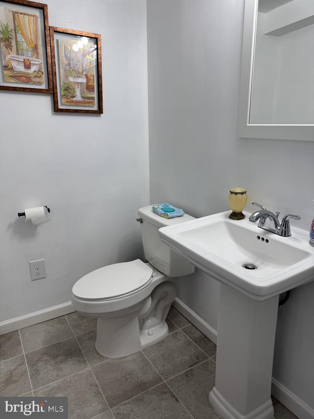 half bathroom featuring toilet, baseboards, and a sink