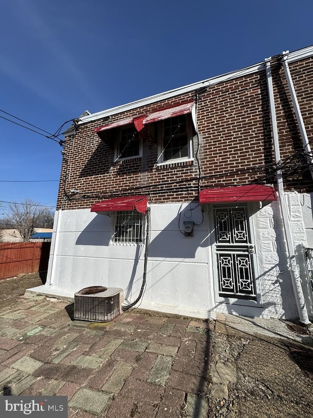 rear view of house featuring fence, a patio, and brick siding