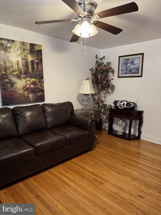 living area featuring baseboards, ceiling fan, and light wood-style floors