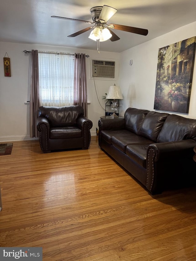 living area with light wood-style floors, a wall unit AC, and a ceiling fan