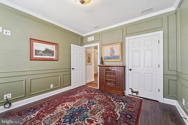 interior space featuring ornamental molding, visible vents, a decorative wall, and dark wood-style floors