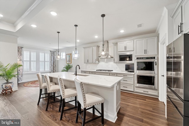 kitchen with double oven, ornamental molding, a sink, built in microwave, and wall chimney exhaust hood