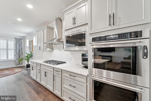 kitchen with visible vents, appliances with stainless steel finishes, wall chimney exhaust hood, tasteful backsplash, and dark wood finished floors