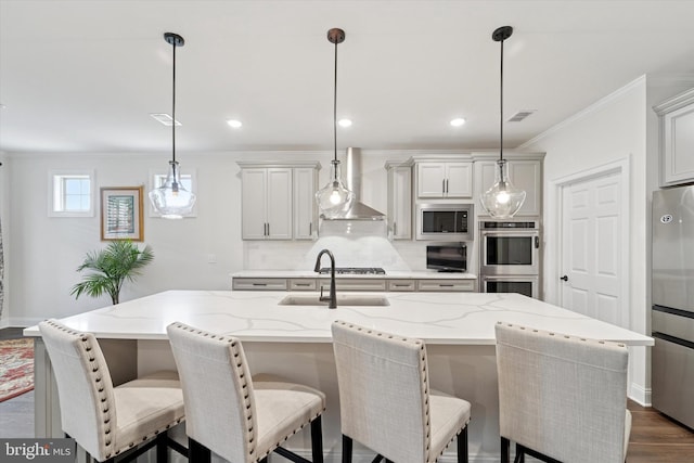 kitchen featuring dark wood-style flooring, stainless steel appliances, visible vents, a sink, and wall chimney range hood