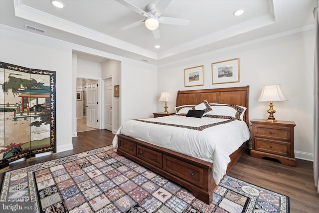 bedroom with visible vents, a raised ceiling, wood finished floors, and ornamental molding