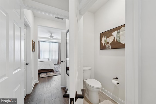 bathroom with toilet, wood finished floors, visible vents, baseboards, and ensuite bath