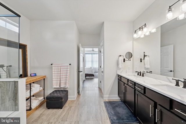 ensuite bathroom featuring ensuite bathroom, double vanity, a sink, and baseboards