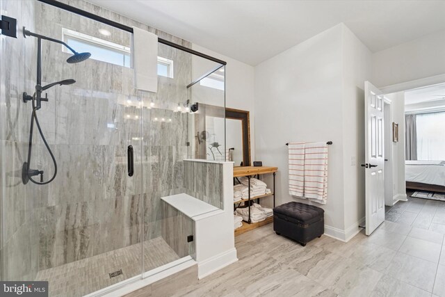 ensuite bathroom featuring baseboards, ensuite bath, and a shower stall