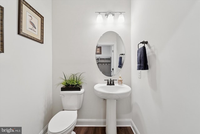 bathroom featuring a sink, wood finished floors, toilet, and baseboards