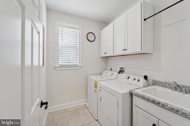 clothes washing area with light tile patterned floors, cabinet space, a sink, separate washer and dryer, and baseboards