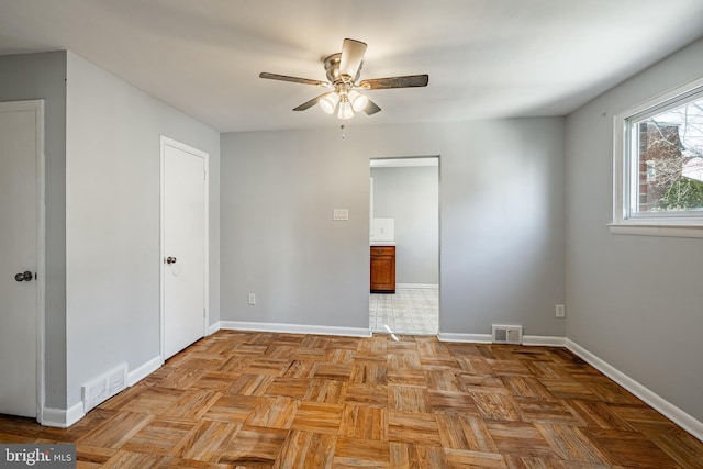 spare room featuring a ceiling fan, visible vents, and baseboards