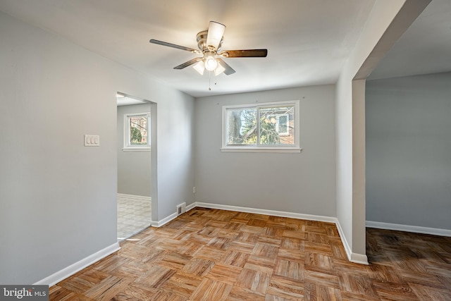 empty room featuring plenty of natural light, visible vents, baseboards, and ceiling fan