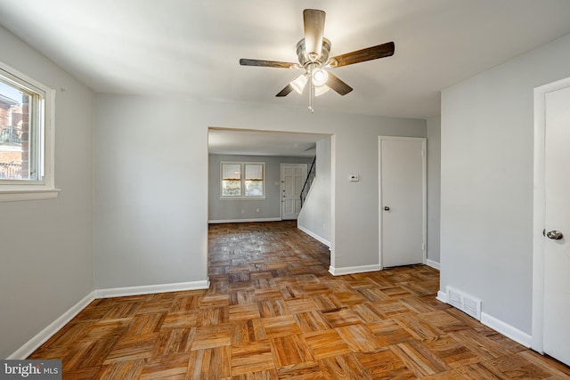 unfurnished room with a ceiling fan, visible vents, and baseboards