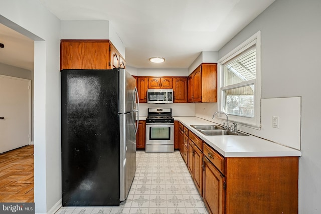 kitchen with light floors, light countertops, brown cabinets, stainless steel appliances, and a sink