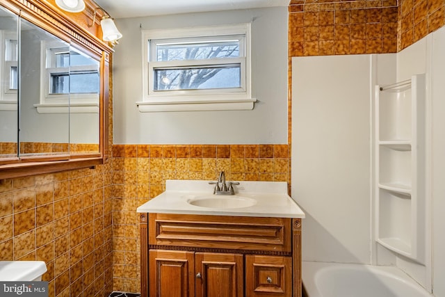 full bath with tile walls, wainscoting, and vanity