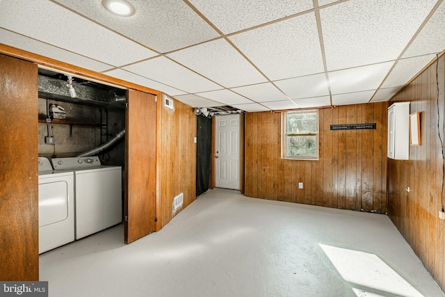 basement with visible vents, wood walls, independent washer and dryer, and a drop ceiling