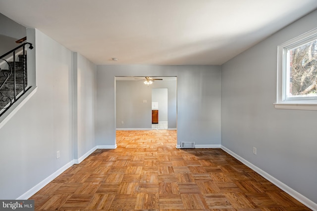 empty room featuring stairs, visible vents, baseboards, and ceiling fan