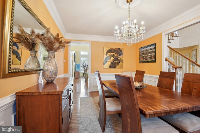 dining space featuring a chandelier, a wainscoted wall, dark wood-type flooring, ornamental molding, and stairway