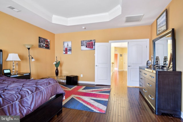 bedroom featuring dark wood-style floors, a raised ceiling, visible vents, and crown molding