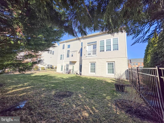 rear view of house featuring brick siding, a yard, and a fenced backyard