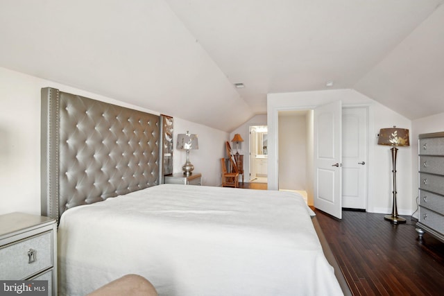 bedroom with vaulted ceiling, visible vents, dark wood finished floors, and baseboards