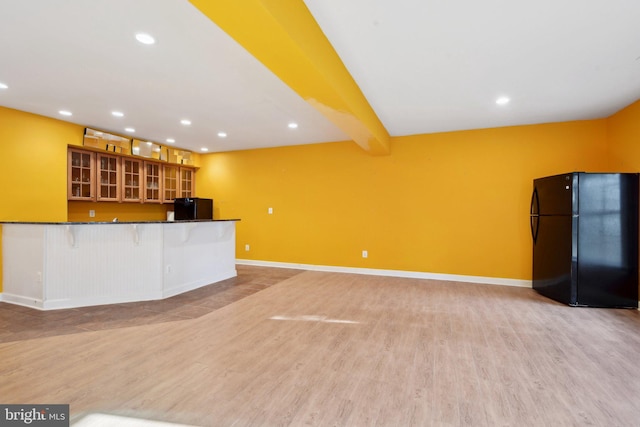 kitchen featuring beam ceiling, dark countertops, glass insert cabinets, freestanding refrigerator, and black fridge