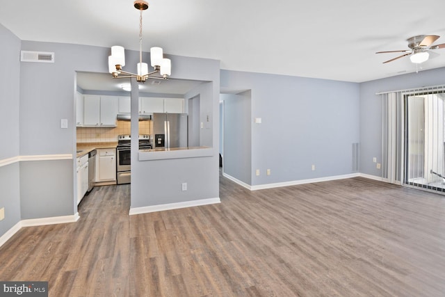 kitchen with wood finished floors, ceiling fan with notable chandelier, stainless steel appliances, white cabinets, and visible vents