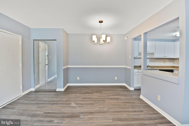unfurnished dining area with baseboards, a chandelier, and dark wood finished floors