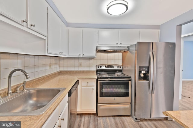 kitchen featuring range hood, light countertops, wood finished floors, a sink, and appliances with stainless steel finishes